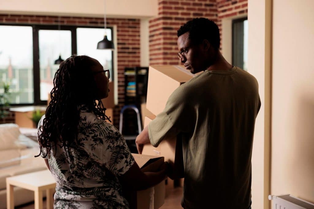 african american partners carrying belongings move new apartment property using boxes decorate rented household moving house together start new beginnings loan